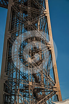 View of one legÃ¢â¬â¢s iron structure of the Eiffel Tower, with sunny blue sky in Paris. photo